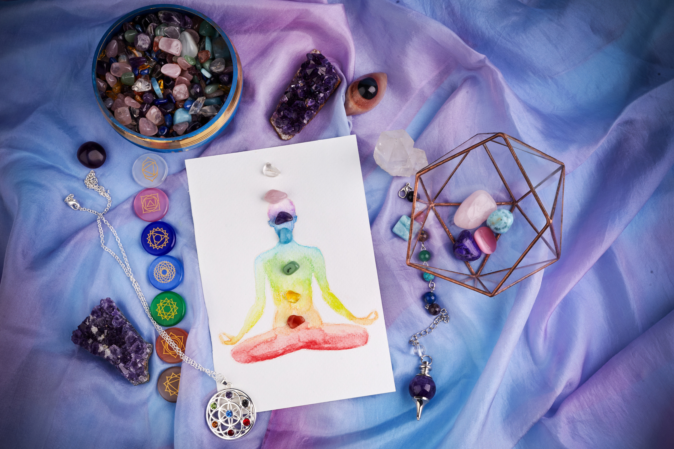 Natural crystals and pendulum on pastel silk background. Reiki background with card.